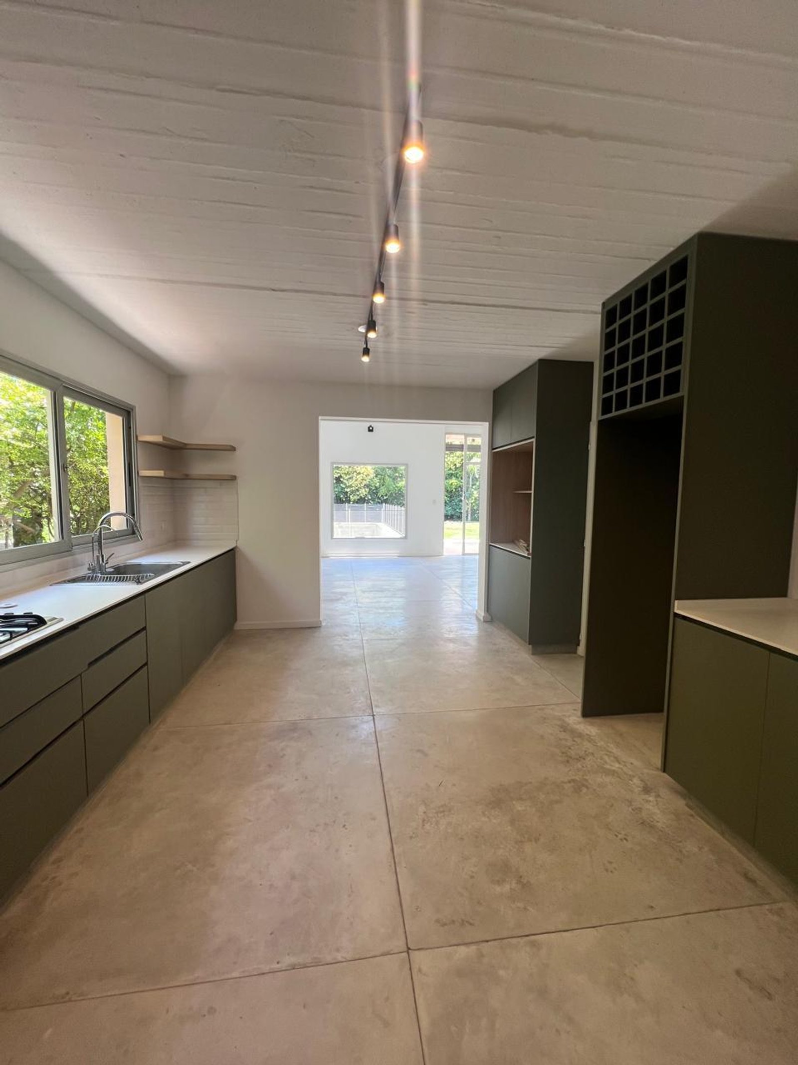 Cozinha moderna com ilha, armários verdes e piso de cimento polido — projeto El lucero, por Estudio NET Arquitectura, em Av. Patricias Argentinas